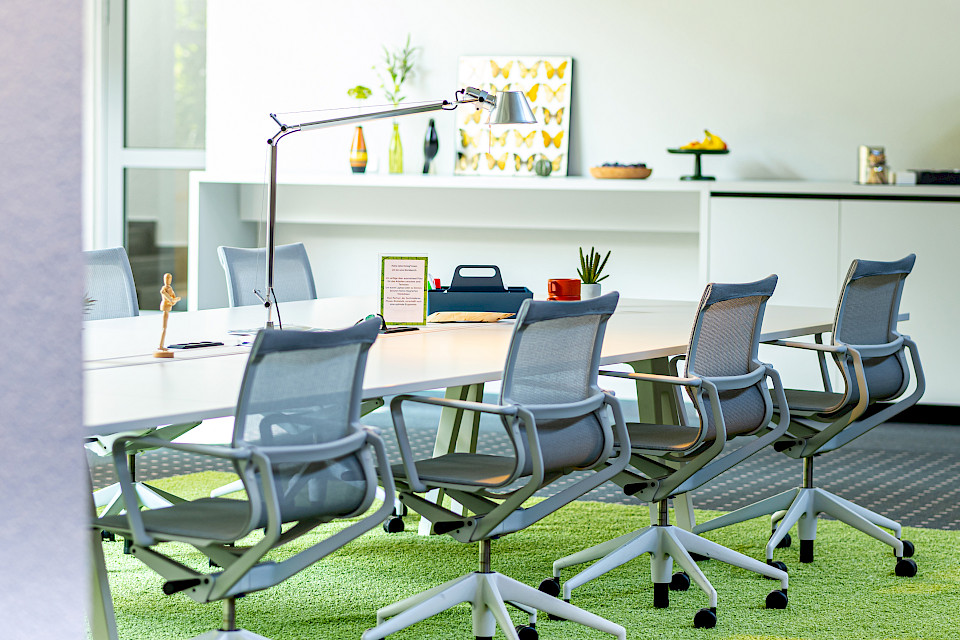 Modernes Foyer mit ergonomischen Stühlen, großem Konferenztisch und heller Atmosphäre.
